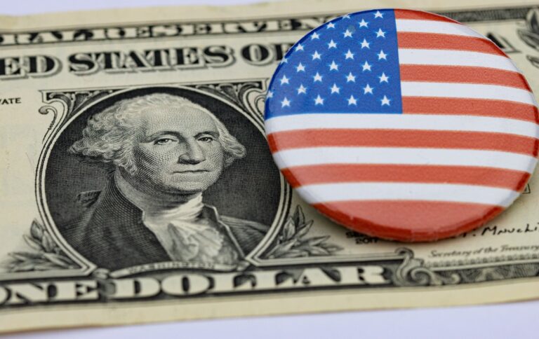 a one dollar bill and a button with the american flag on it