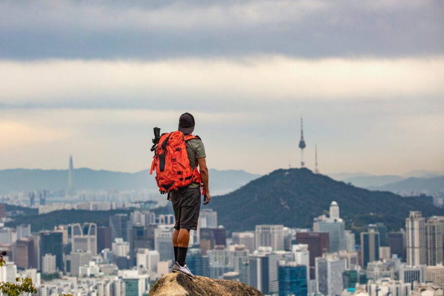 Back View of a Man with a Backpack Standing on Top of the Ansan Mountain and Looking at the City of Seoul, South Korea 