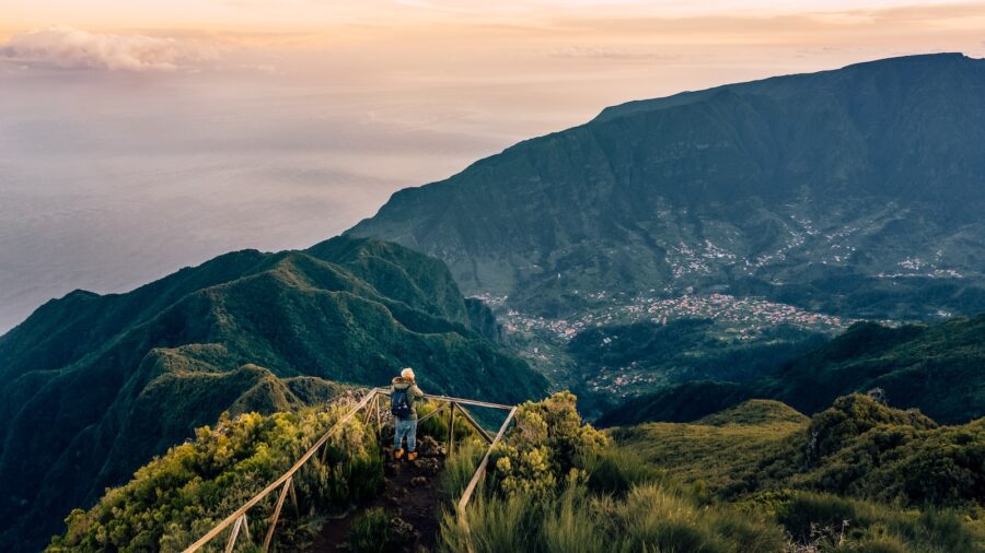 aerial photography of person on cliff overlooking mountains