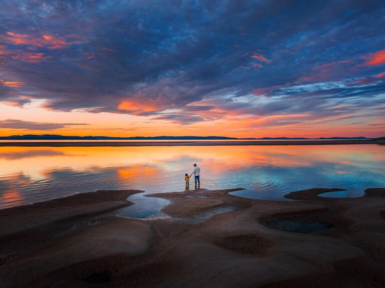 two people standing in the water at sunset
