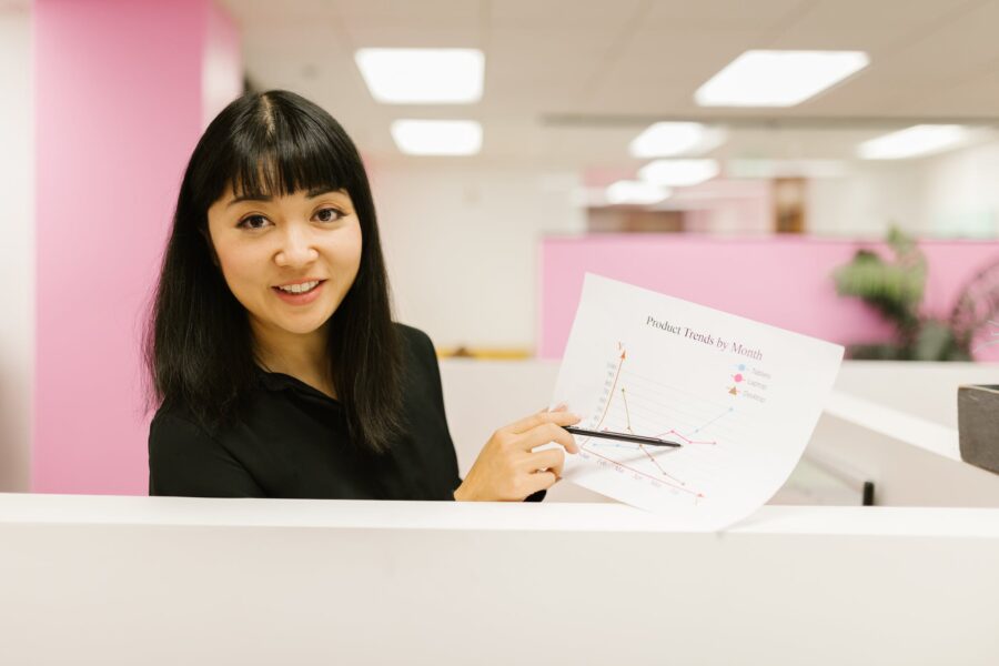 Woman Pointing Black Pen on White Paper with Graph