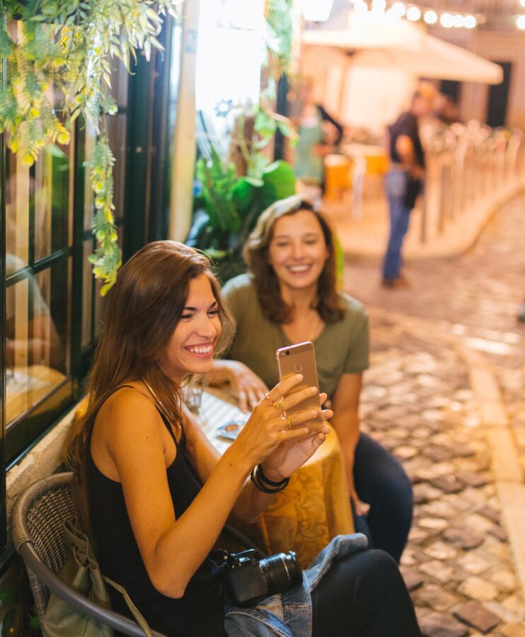 Woman Taking Photo in Front of Woman Across Table Selective Focus Photography
