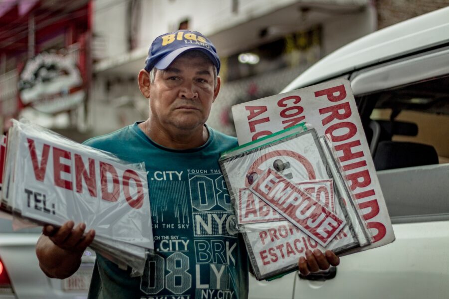a man holding two signs in front of a car