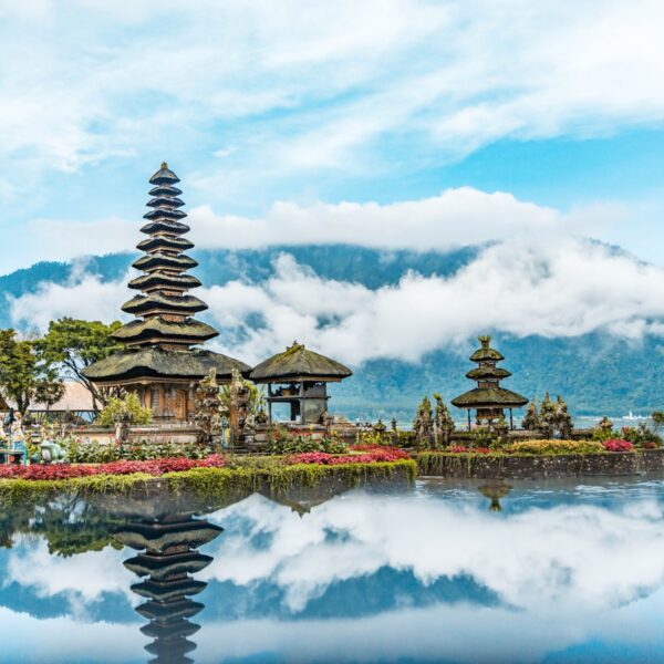 brown and green temple near body of water under blue and white cloudy sky during daytime