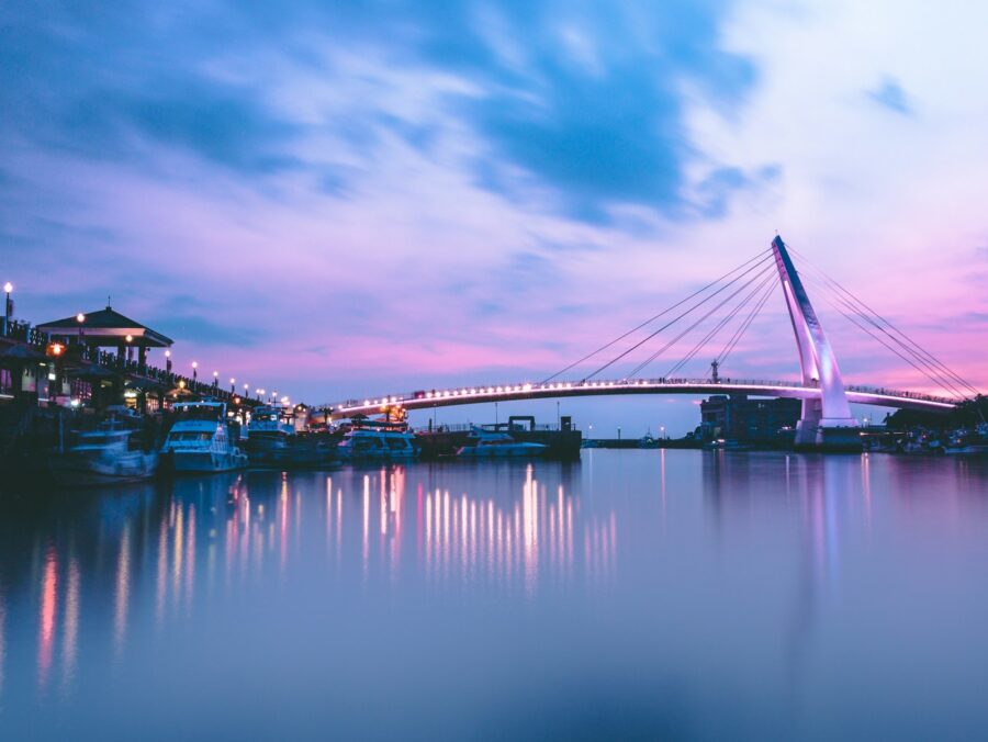 gray bridge with lights near boat at daytime