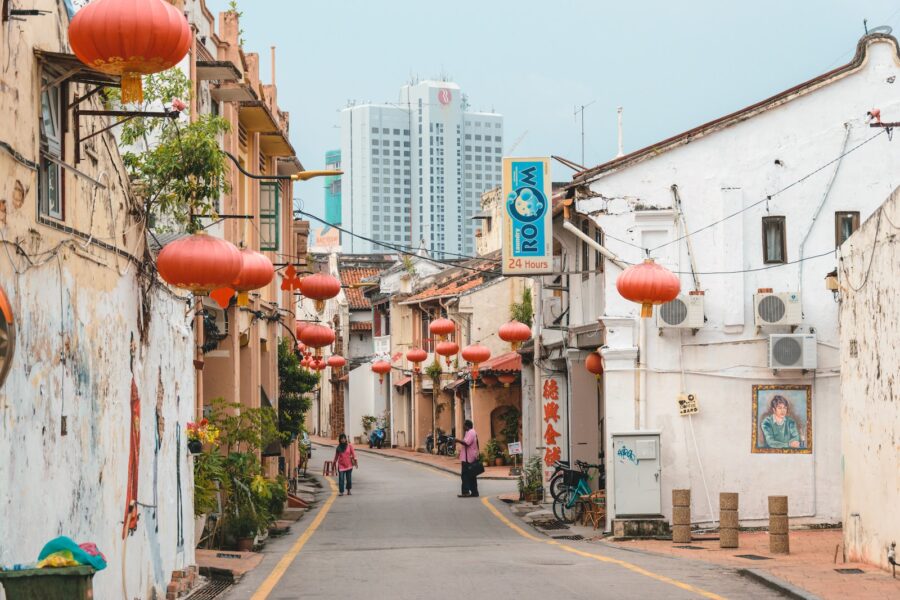 a narrow street with chinese lanterns hanging from the buildings