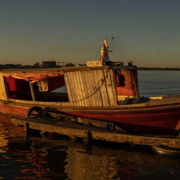brown and red boat on water during sunset