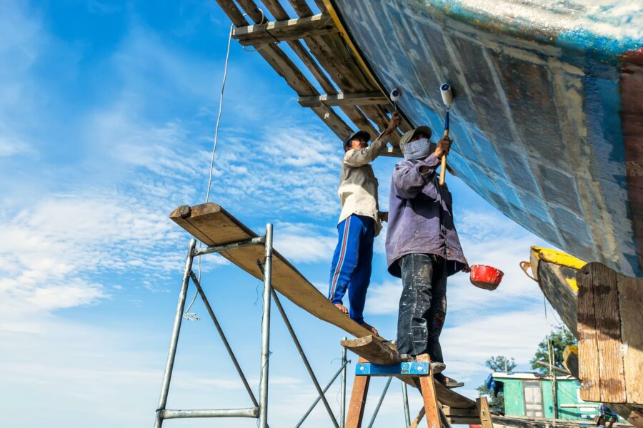 Two men are working on a boat in the water