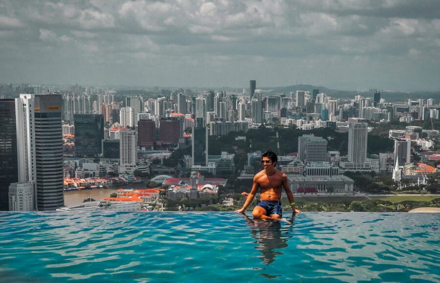 woman in black bikini top sitting on swimming pool during daytime
