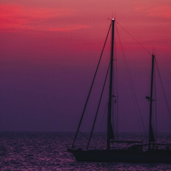 silhouette of sail boat on sea during sunset